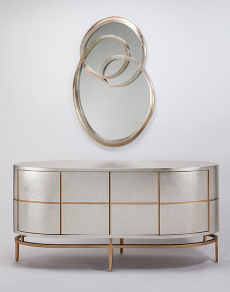 Decorative mirror with circular design above a metallic sideboard on a light gray background