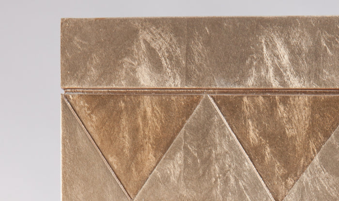 Close-up of a decorative tile with geometric pattern on a gray background