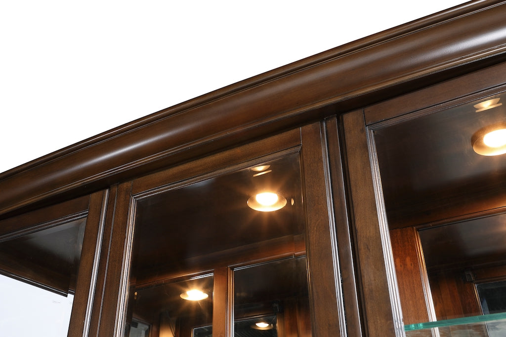 Close-up of a wooden cabinet with glass doors and lights inside.