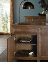 Wooden sideboard with open drawer displaying books, against a blurred indoor background.