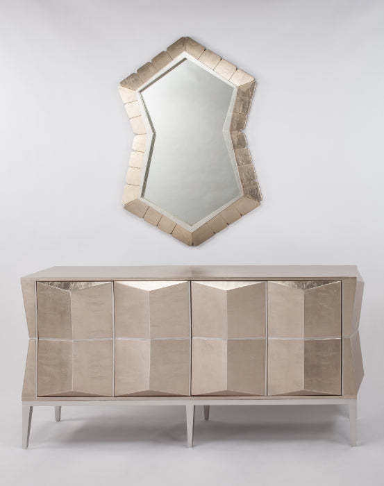 Decorative mirror with geometric design above a mirrored console table on a white background