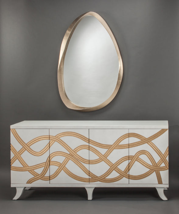 Decorative cabinet with gold wavy patterns and an oval mirror above on a gray background