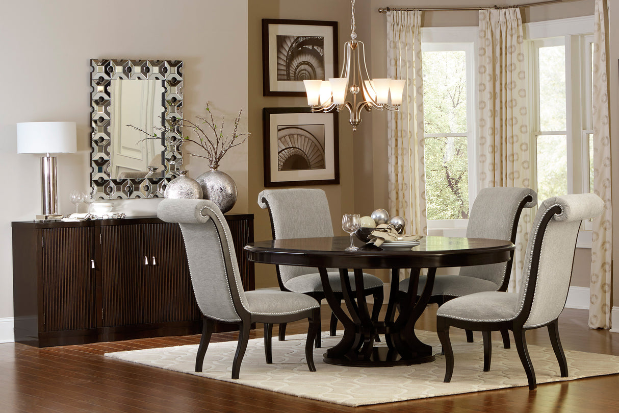 Dining room with a round wooden table and gray chairs, featuring a chandelier and sideboard.