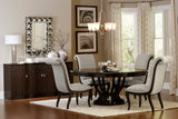 Dining room with a round wooden table and gray chairs, featuring a chandelier and sideboard.