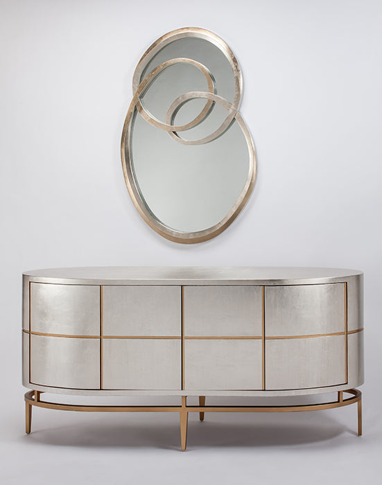 Decorative mirror with circular design above a metallic sideboard on a light gray background