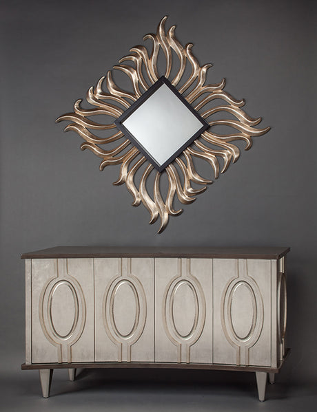Decorative wall mirror with a sunburst design above a wooden cabinet against a gray background