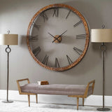 Large wall clock with Roman numerals in a room with a bench and lamps.