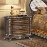 Decorative nightstand with ornate design next to a bed with patterned bedding.